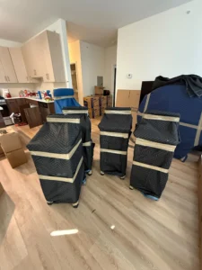 Stacked moving boxes wrapped in protective covers inside an empty room