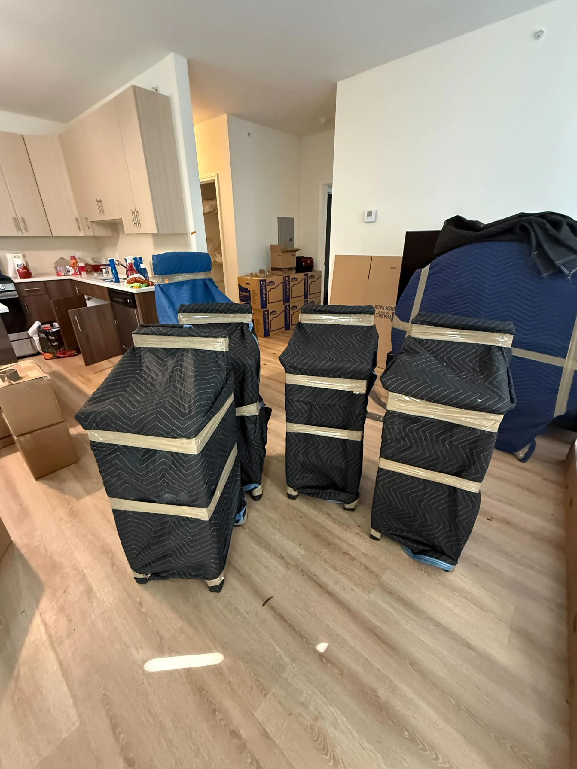 Stacked moving boxes wrapped in protective covers inside an empty room