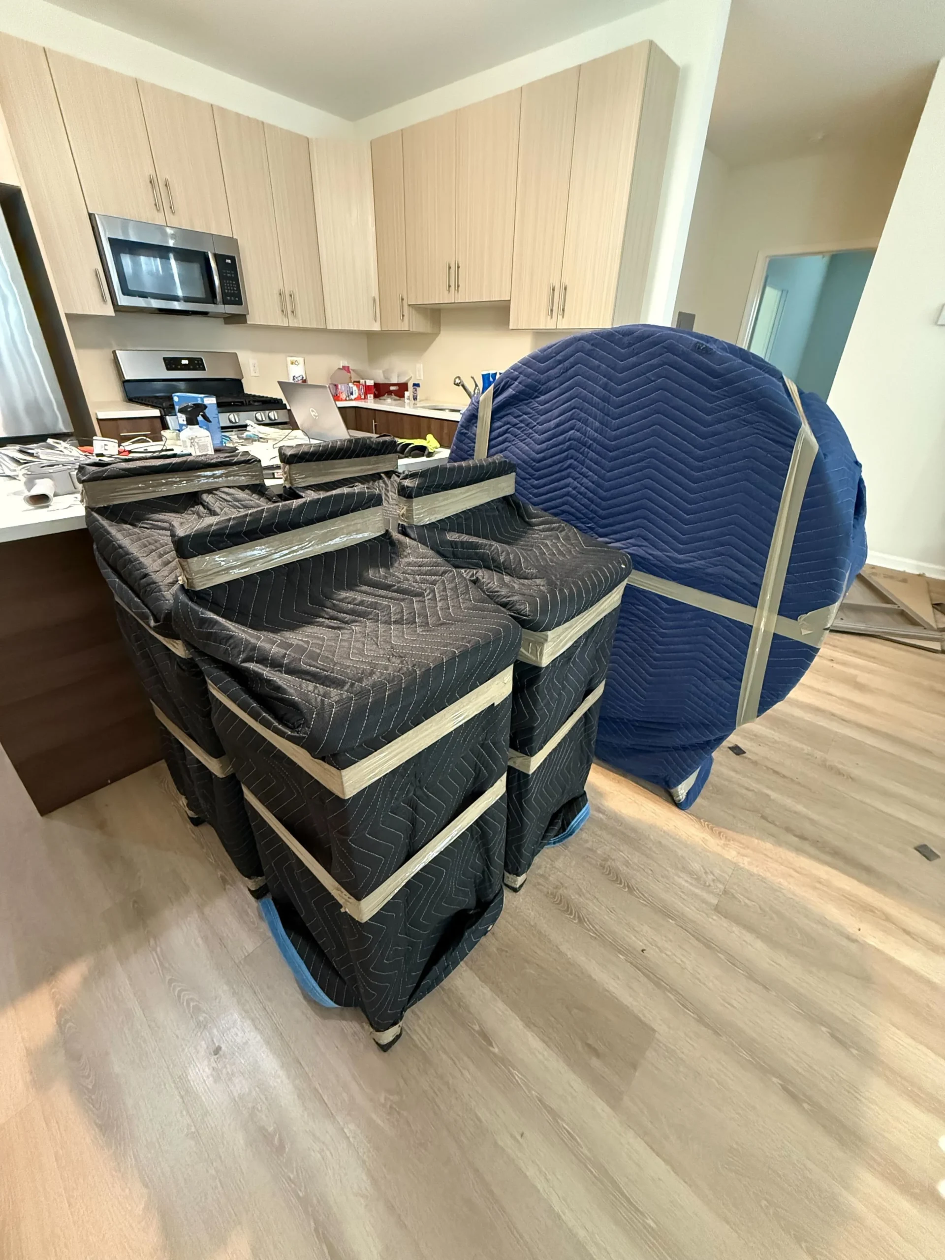 Moving blankets stacked around furniture in a kitchen setting